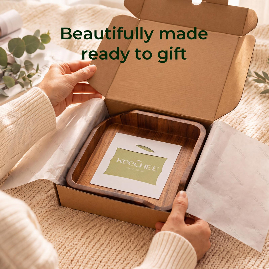 Hands opening a gift box containing a KEECHEE acacia wood napkin holder and guide card